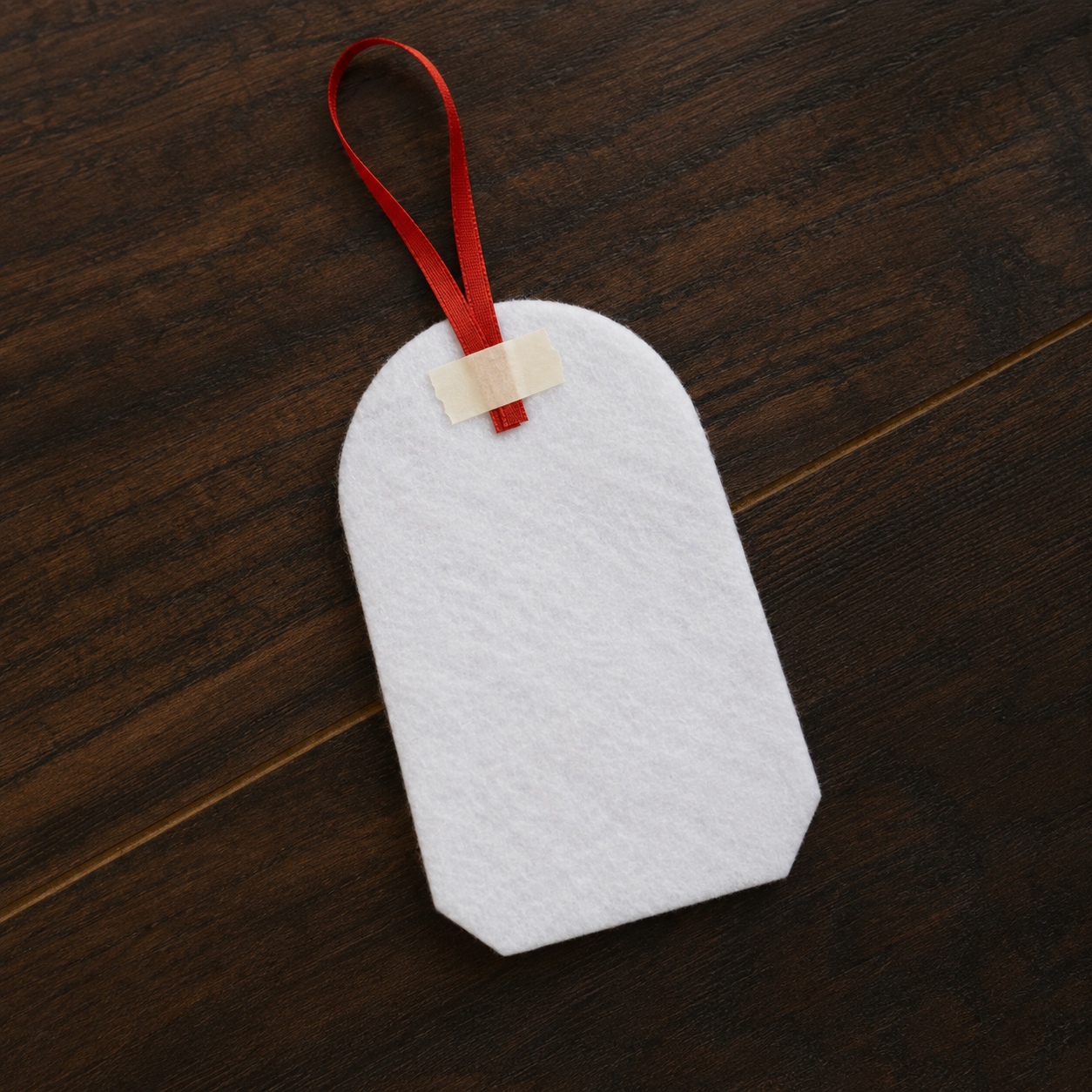 Red ribbon loop taped to the back felt piece of a Christmas ornament