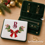 Digital machine embroidery design with a symmetrical Christmas arrangement: a large red bow with a gold outline sits in the centre, surrounded on both sides by fir branches, deep green holly leaves, red berries, brown twigs and olive-gold sprigs. The motif suits the front of a gift bag, a napkin, a smooth towel band, a cushion front or another flat festive textile panel. The letter in the presentation image is shown separately as a personalization example and is not part of this design. The archive contains four original ready-to-stitch file sizes for an embroidery machine; it is not a finished textile product.